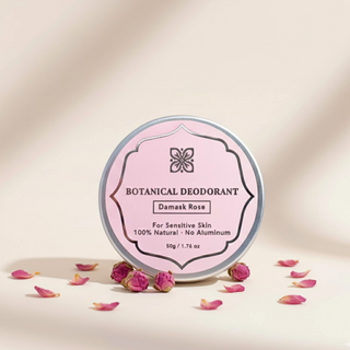 Damask Rose Botanical Deodorant tin for sensitive skin displayed with dried rose petals and rosebuds on a warm tan background.
